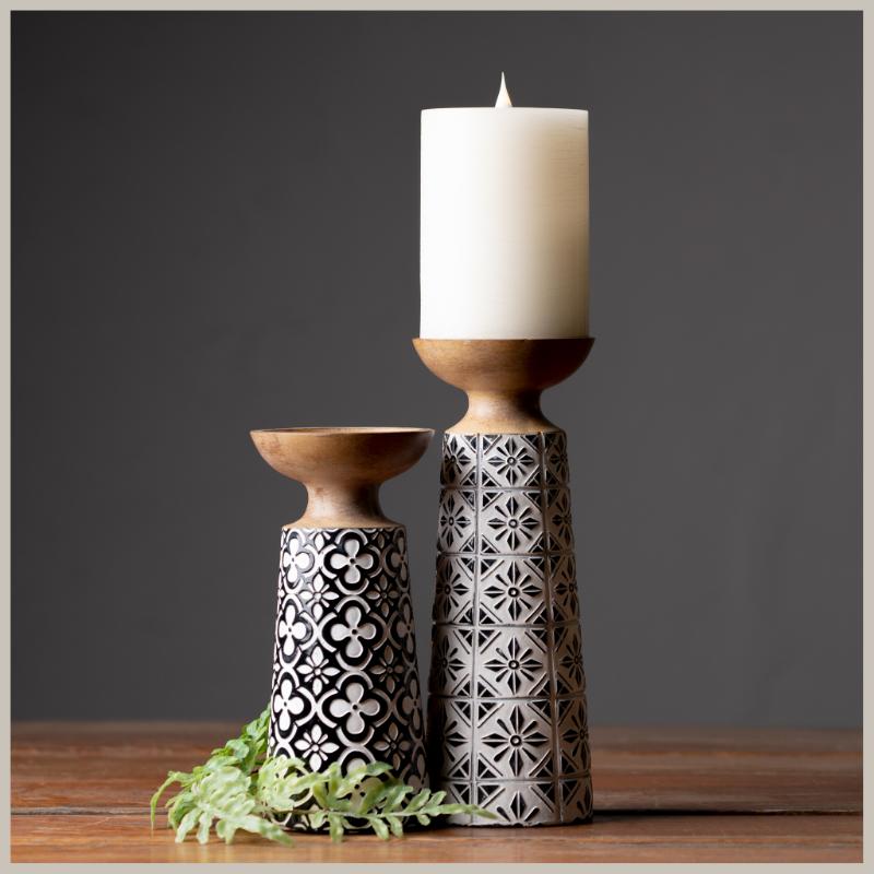 Pair of resin pillar candle holders with black and white floral geometric designed bodies. 