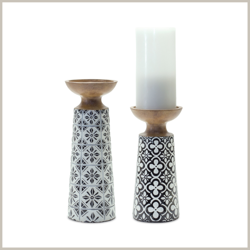 Pair of resin pillar candle holders with black and white floral geometric designed bodies.