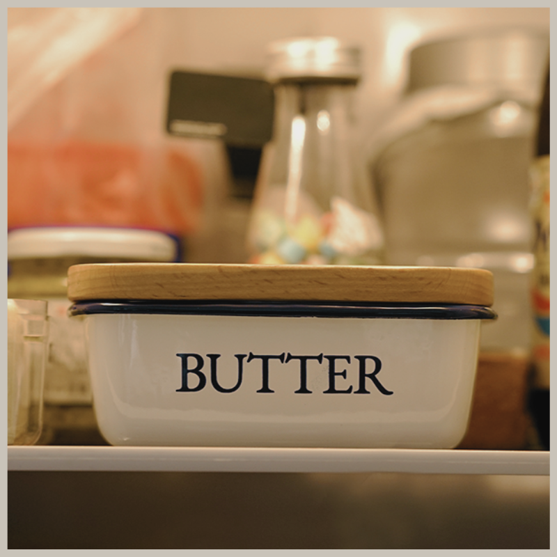 Blue and white Shaker style enamel butter dish. Photo shows dish and wooden lid on a shelf in refridgerator. 