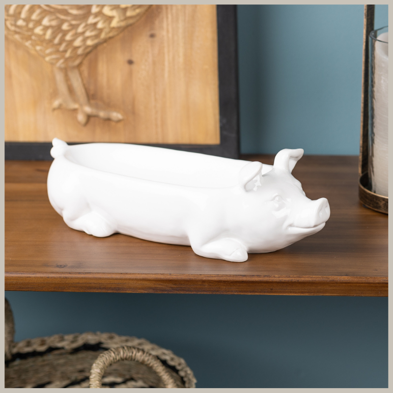 A large white ceramic pig planter sitting on a wood table. 
