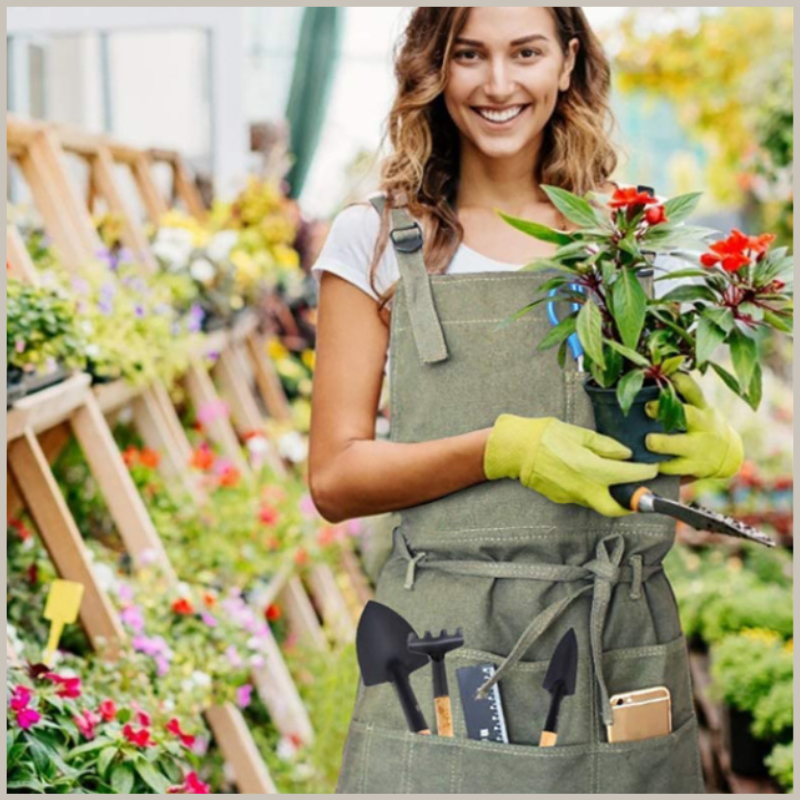 Model wearing apron in greenhouse. Pockets holding gardening tools. 